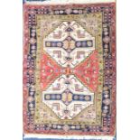 Two Persian red ground woollen rugs decorated with geometric patterns and surrounded by floral