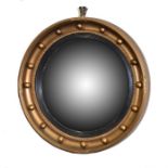 A Regency style convex wall mirror of circular form set within a gilded beaded border. 42 cm in