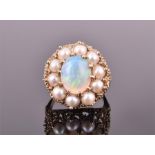A yellow gold, opal, and pearl cluster ring centred with an oval cabochon opal surrounded by pearls,