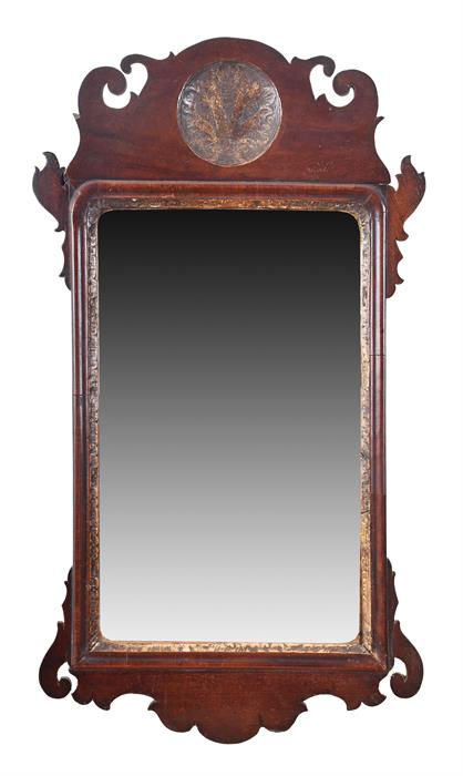 An 18th century walnut wall mirror with a scrolled and shaped frame, with gilt roundel. 68 cm high.