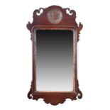 An 18th century walnut wall mirror with a scrolled and shaped frame, with gilt roundel. 68 cm high.