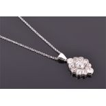 A white metal and diamond Art Deco cluster pendant centred with an old cut diamond, surrounded by