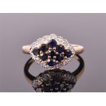 A 9ct yellow gold, diamond, and sapphire cluster ring set with nine round cut sapphires framed