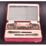 A cased silver manicure set comprising of buffer, two glass jars, tweezers, and cuticle pusher,