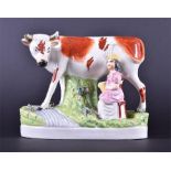 A 19th century Staffordshire figure group of a seated milkmaid beside a standing cow 17 cm tall,