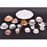 A collection of various porcelain cabinet miniatures to include cups, saucers, a tea seat
