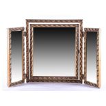 A gilt three-fold dressing table mirror with moulded leaf decoration.