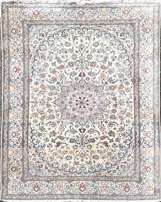 A Persian ivory ground silk and wool Isfahan carpet decorated with a central floral roundel