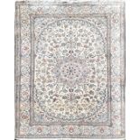 A Persian ivory ground silk and wool Isfahan carpet decorated with a central floral roundel