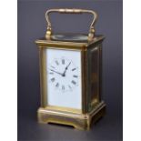 A 20th century brass carriage clock with bevelled glass panels, the white dial with Roman