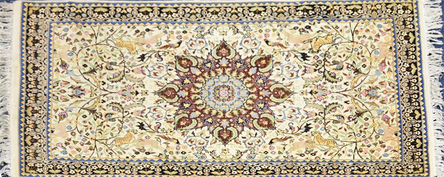 An Eastern ivory ground wool rug centred with a complex medallion, encircled by symmetrical trailing