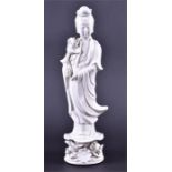 A Chinese blanc de chine porcelain figure of Guanyin holding a lotus flower, supported on