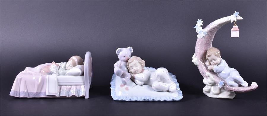 A trio of Lladro figurines of sleeping children one has made his bed on a crescent moon, a lamp
