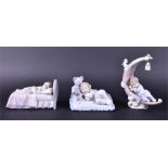 A trio of Lladro figurines of sleeping children one has made his bed on a crescent moon, a lamp