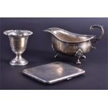 Three silver items  to include an egg cup, cigarette case and sauce boat, 10.6 ozt.