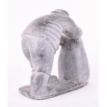 An unusual carved stone Inuit figure depicting a man leaning over working, 22.5 cm long.