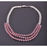 A white metal, diamond, and ruby triple strand necklace comprising of three rows of alternating