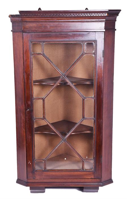 A small mahogany astragal glazed corner cupboard the hinged front revealing a shelved interior,