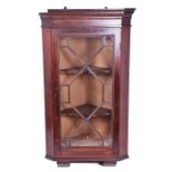 A small mahogany astragal glazed corner cupboard the hinged front revealing a shelved interior,