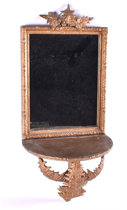 A small Victorian gilt wood wall sconce, backed by a framed mirror decorated with applied fern