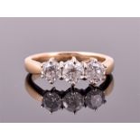 A yellow metal and three stone diamond ring set with three round brilliant cut diamonds of