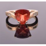 A 9ct yellow gold, diamond, and andesine ring set with a trillion cut orange/red andesine of