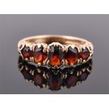 A 9ct yellow gold and garnet ring set with five graduated oval cut stones in decorative mount,