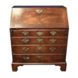 A Georgian mahogany bureau the base fitted with four drawers with pierced brass handles, supported