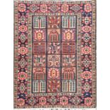 An old Eastern woven wool rug the red ground populated with squared medallions decorated with