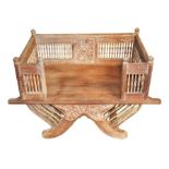 An Eastern hardwood platform dog bed with carved decoration and turned spindles, supported on X