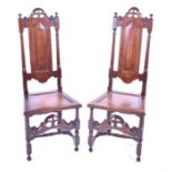 A pair of late 17th or early 18th century oak tall back hall chairs the central panel backs with