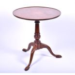 A George III mahogany supper table the plain snap top with moulded rim and supported on a turned and