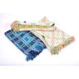 Three large Welsh wool rugs in patterned fabric, two in green and brown, and one in dark blue and