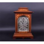 An Edwardian mahogany arch-top mantel clock the white enamel dial with black Roman numerals,