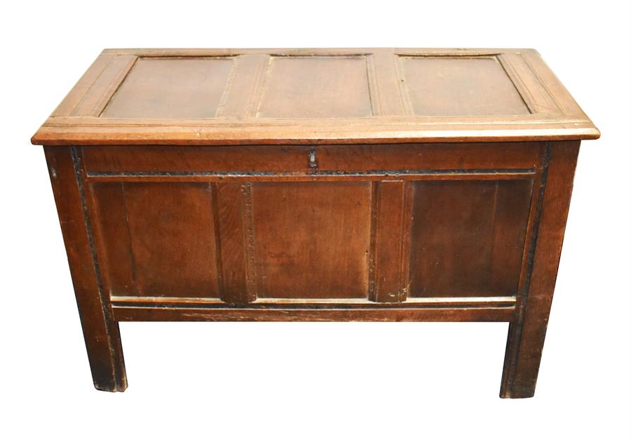 A 19th century oak chest with hinged three-panelled lid, panelled sides, raised on four straight