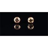 A pair of yellow metal and cognac diamond solitaire stud earrings collet set with round cut stones