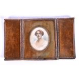 An early 20th century oval portrait miniature of a lady in a gilt frame set in a hinged leather