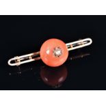 A late 19th / early 20th century coral and diamond bar brooch set with a round polished coral