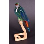 A Swarovski crystal macaw in red, blue, and chrome green, with white metal beak,  perched on