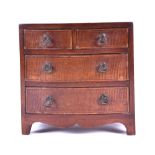 A miniature veneered chest of drawers two small over two large drawers, bowed front, brass handles