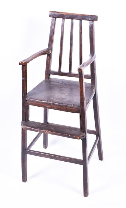 A childs 18th century elm high chair of simple naive form, the triple spindle back with open arms,