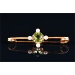 A yellow metal, peridot, and pearl bar brooch set with a fancy cut peridot of approximately 2.0