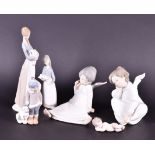 Two Lladro figures of seated cherubs in robes together with a small Lladro figure of a boy with a