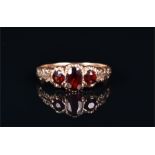 A 9ct yellow gold and garnet ring set with an oval cut garnet flanked by two round cut garnets,