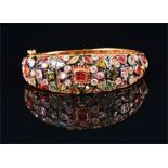 An Indian gold metal and gemstone bangle the filigree mount set with various semi-precious