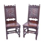 A pair of 18th century carved oak hall / side chairs the backs elaborately carved with flowers and