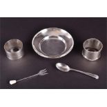 A small quantity of silver items to include a round dish, two napkin rings, a small teaspoon, and