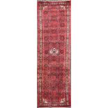 A Persian red ground runner centred with central floral medallion and complex geometric designs,