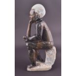 A large African carved hardstone figure of a seated man with a pipe, numbered '325' to base, 42cm.