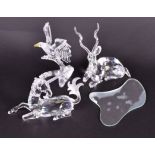 A collection of three Swarovski crystal animals including a bald eagle seated on a branch, a